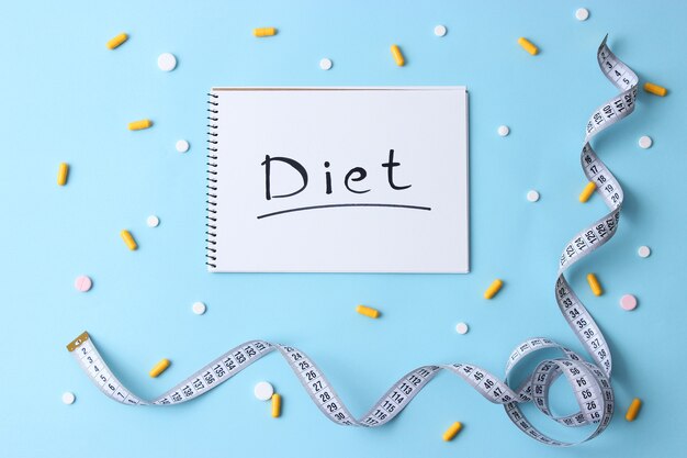 Measuring tape and diet pills on a colored background closeup