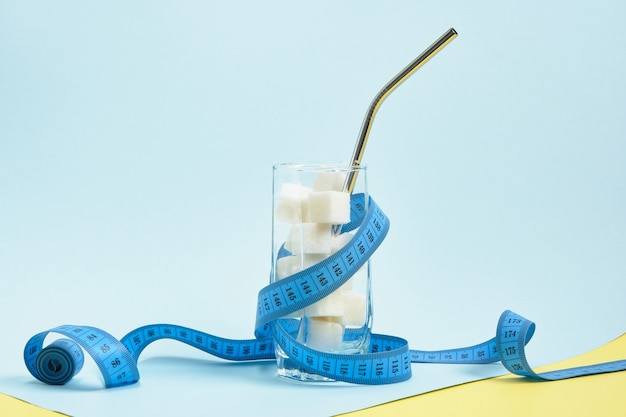 measuring tape and glass with sugar cubes and cocktail tube 