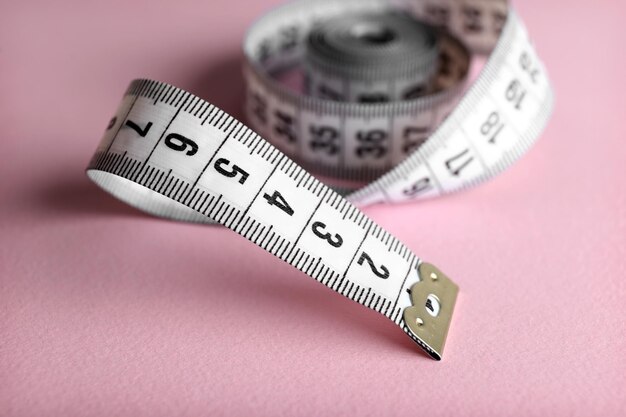 Measuring tape on pink background