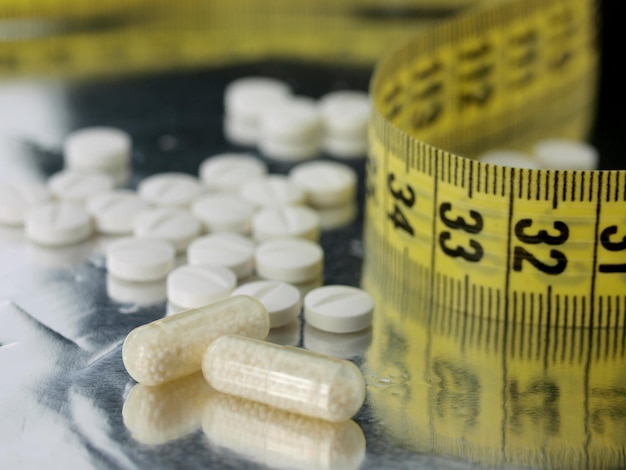 Photo a measuring tape with pills on it is on a table.