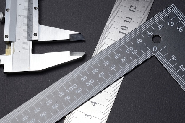 Photo measuring tool, ruler square and caliper. lie on a dark background. close-up.