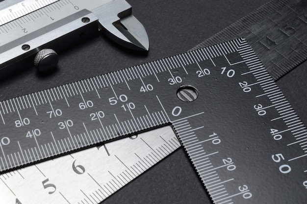 Measuring tool, ruler square and caliper. lie on a dark background. close-up.