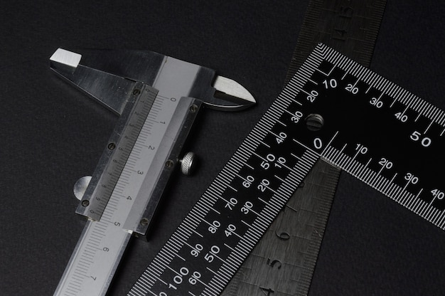 measuring tool, ruler square and caliper. lie on a dark background. close-up.