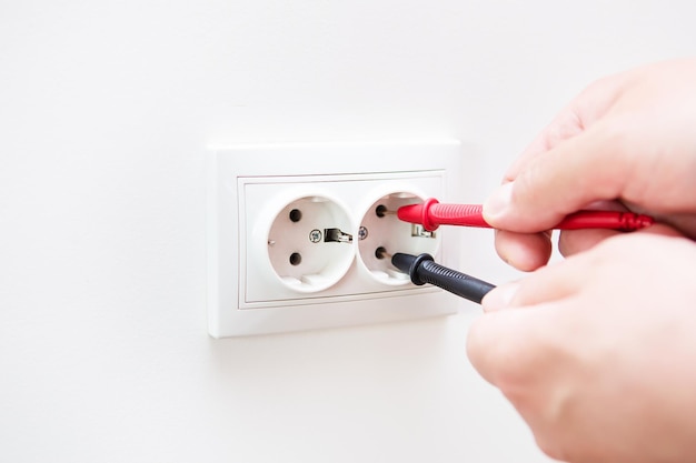 Measuring the voltage in the socket with a professional digital multimeter Profession electrician the process of installing sockets Closeup selective focus noise