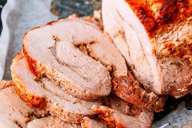 Meat baked on a baking sheet and parchment paper next to a meat fork