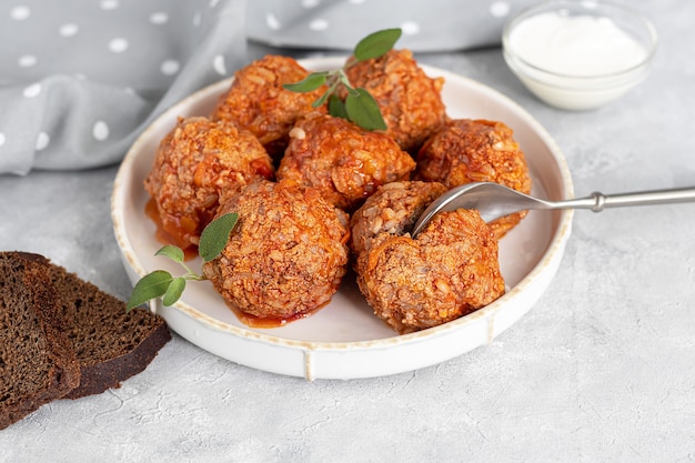 Meat balls on a light background with sage and parsley leaves. Homemade lunch.