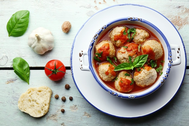 Photo meat balls with tomato sauce and ingredients on wooden background