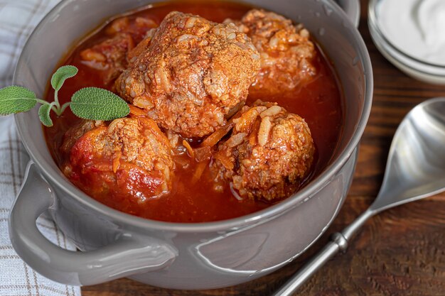 Meat balls on a wooden background with sage and parsley leaves. Homemade lunch.