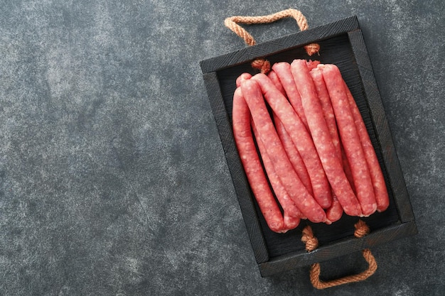 Meat beef sausages Raw barbecue sausages with spices vegetables and ingredients for cooking on black background Top view Copy space Oktoberfest menu concept