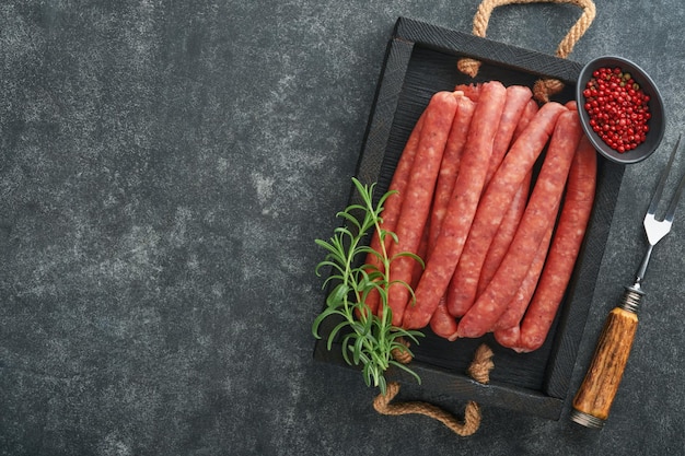 Meat beef sausages Raw barbecue sausages with spices vegetables and ingredients for cooking on black background Top view Copy space Oktoberfest menu concept