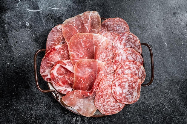 Meat Charcuterie Plate with Prosciutto crudo Salami and Coppa Sausage Black background Top view