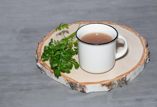 Photo meat or chicken broth in a white ceramic mug on a wooden background broth recipes