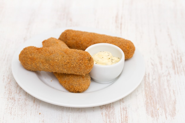 Meat croquets with sauce on white plate