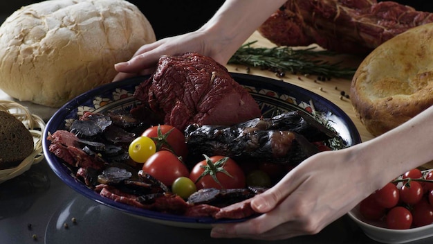 Photo meat cutting on plate with tomatoes scene close up of plate with exquisite cut ham and meat with