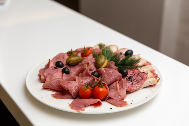 Foto piatto di delicatessen di carne con pomodoro di ciliegio, olive nere e verdi e capperi