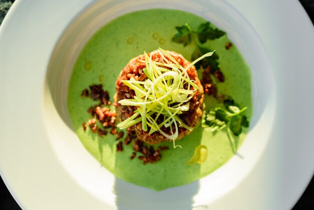 Piatto di carne con riso, fette di cipolle, verdure e salsa