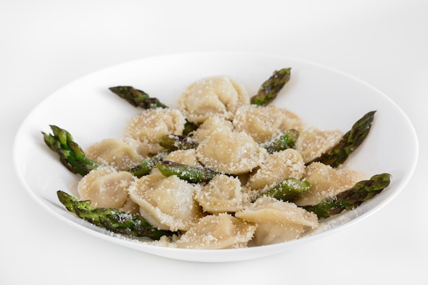 Meat dumplings with parmigiano and asparagus on white plate.