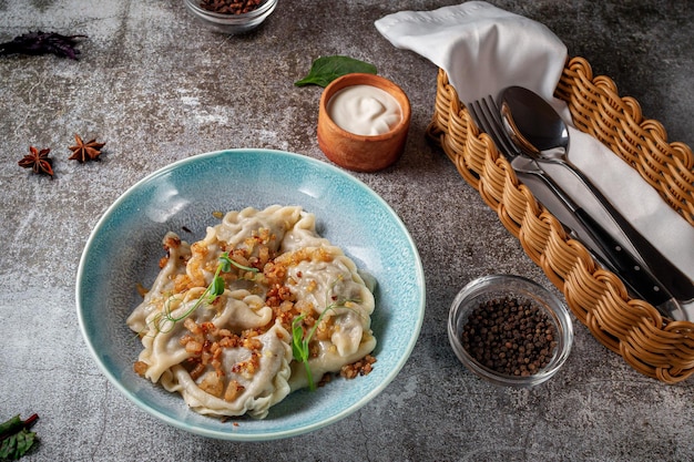 Meat dumplings with spices on a plate with greens against the background of a gray stone table