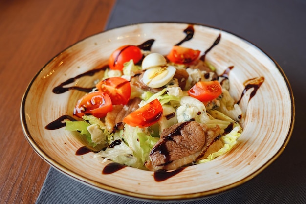 Insalata di carne, uova, lattuga, pomodori e formaggio in piatto bianco, fuoco selettivo. avvicinamento