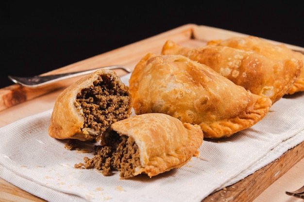 A meat empanada opened in half, in front of more empanadas