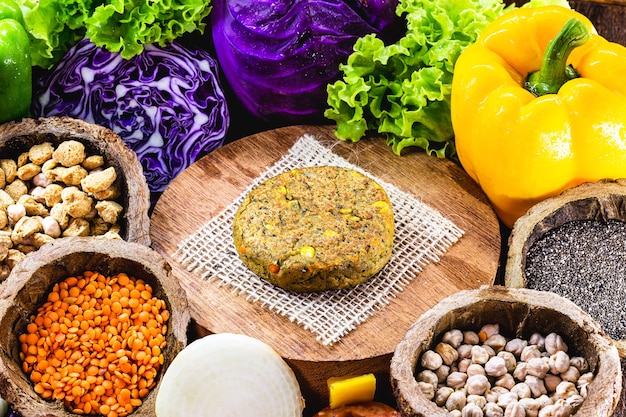 meat-free vegan burger made with seeds, vegetables, soy, chickpeas, corn and lychee, surrounded by vegetables.