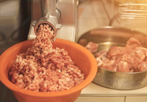 Photo meat grinder mincing fresh raw meat selective focus on an automatic electric meat mincer at home