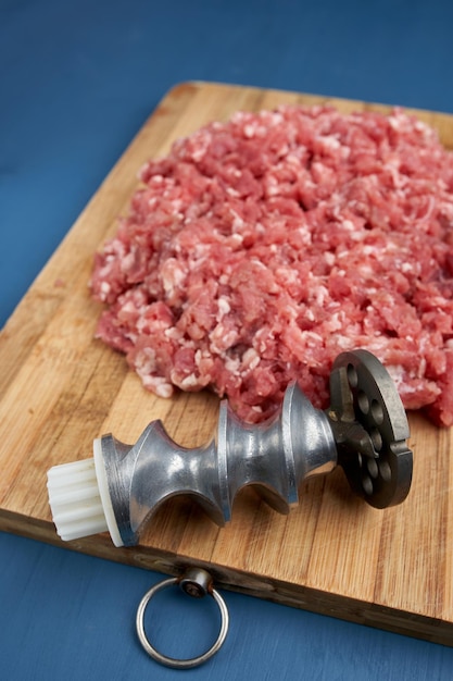 Meat grinder parts and minced meat on a wooden board