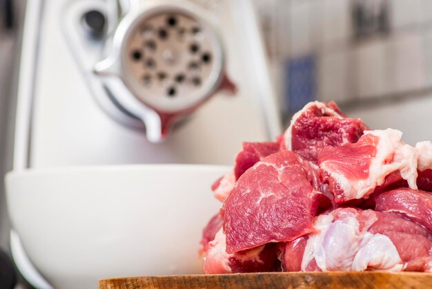 Photo meat grinder with fresh meat on a cutting board in kitchen interior