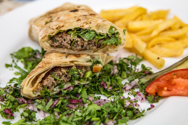 Meat kabab sandwich shawarma wrap filled with onion tomato served in dish isolated on table top view of arabic food