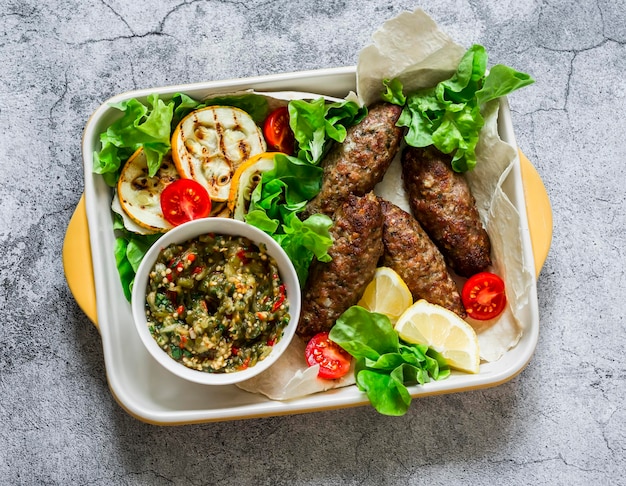 Meat kebab grilled vegetables sauce zucchini flatbread green salad a delicious mediterranean style lunch on a gray background top view