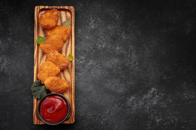 Meat nuggets with ketchup on a dark background