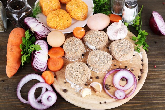 Meat patties on board on wooden table