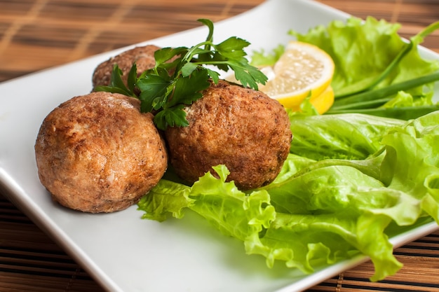 Foto polpette di carne nel piatto con lattuga e prezzemolo