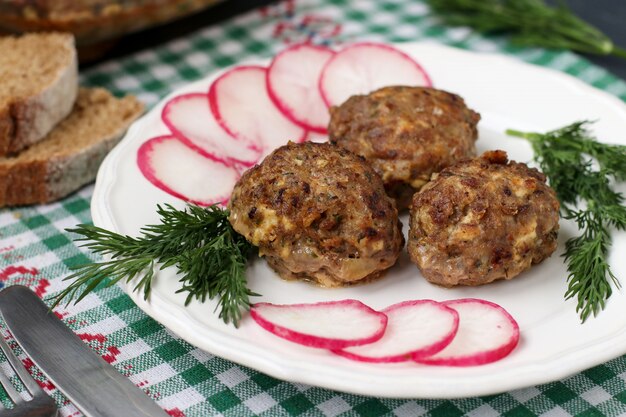 Meat patties and radish on a white plate