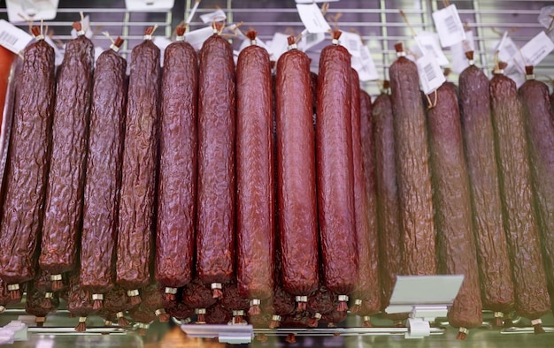 meat products, sale and food concept - salami sausage at grocery store stall