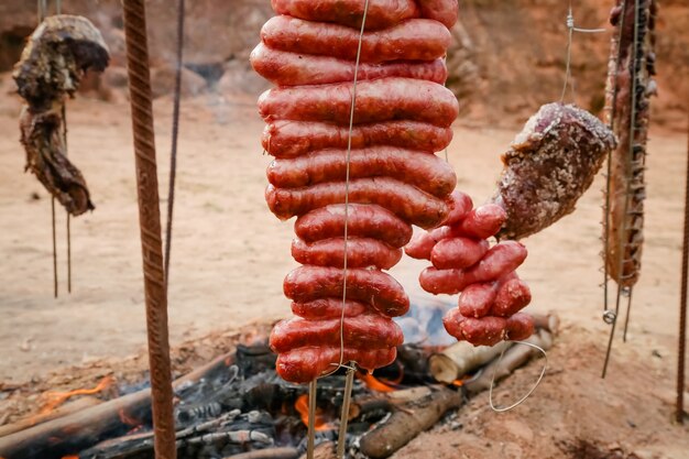 Carne arrosto e tagliata sul tavolo e fuoco di bivacco con legna da ardere in stile gaucho