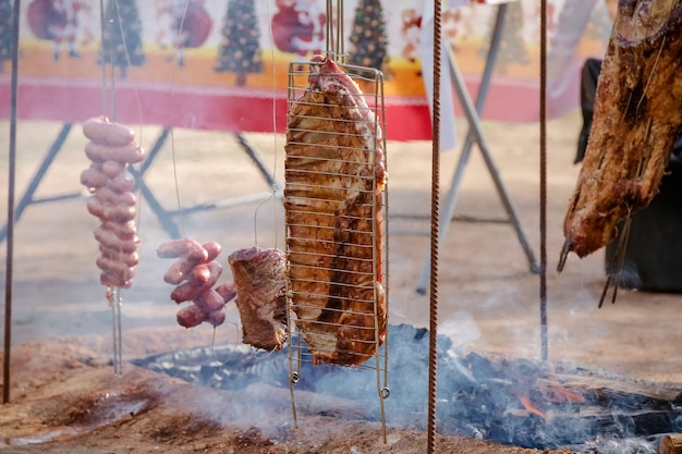 Мясо, запеченное и нарезанное на столе и у костра на дровах гаучо