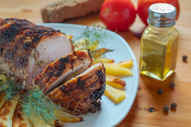 Мясной рулет со специями в тарелке лежит на столе.