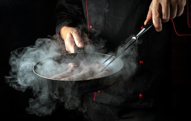 Meat sausage fry The chef prepares a delicious lunch in a steamed hot pan Free space for advertising