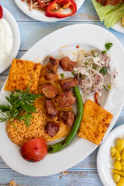 Meat shish kebab in a plate with appetizers top wiev