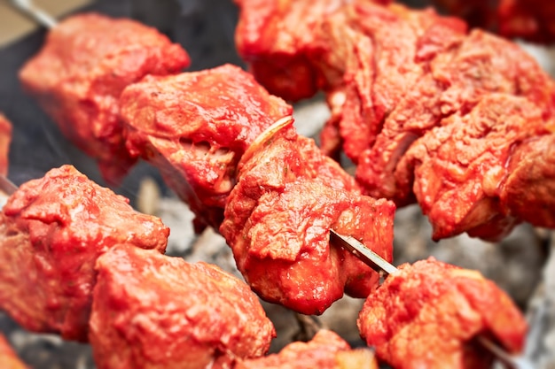 Meat skewers on coals smoke over pieces of meat on skewers\
closeup selective focus