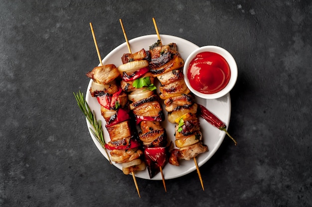 Meat skewers with grilled vegetables on a plate on a stone background
