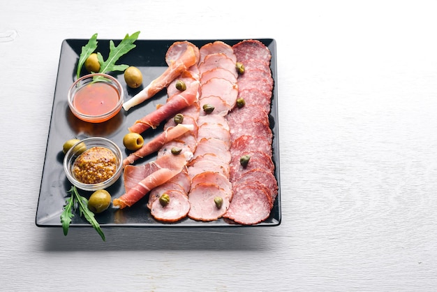 Meat slices on a plate with ketchup and mustard Sausage and bacon On a wooden background Top view Free space