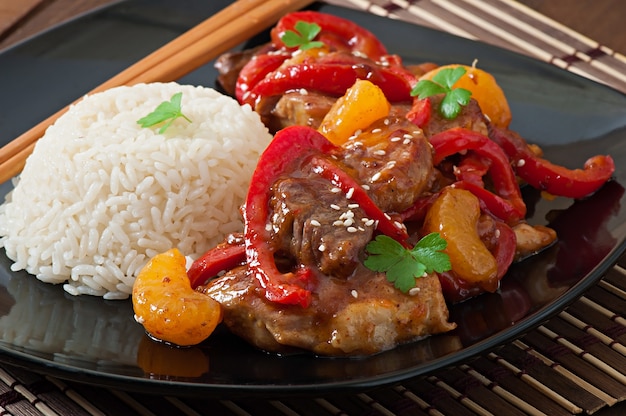 Meat in a spicy sauce, sweet pepper and tangerines with a garnish of boiled rice