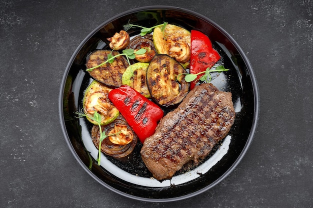 Meat steak with grilled vegetables on a dark plate