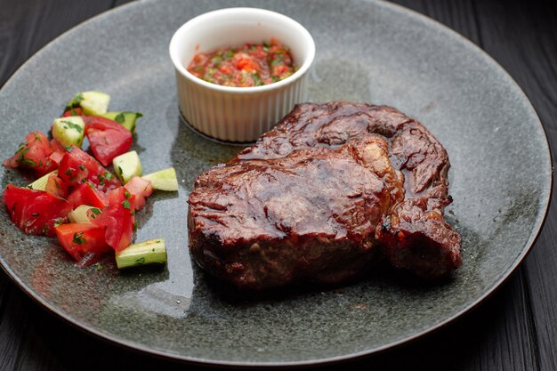 Bistecca di carne con verdure e salsa, su un piatto leggero