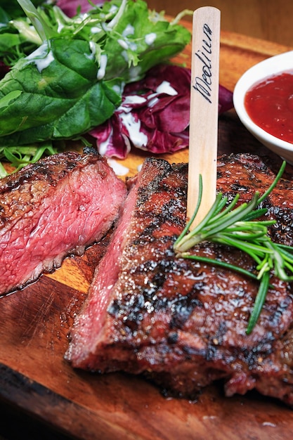 Photo meat steak on the wooden board close up