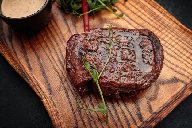 Meat steak on the wooden board on a dark background