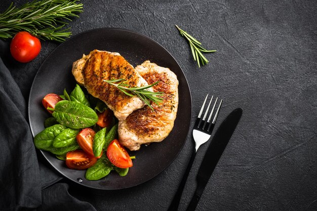 Photo meat steaks with fresh salad top view image at black table