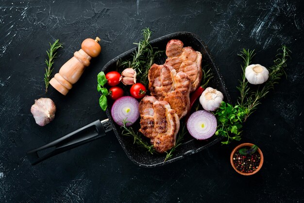 Meat steaks with rosemary Grill barbecue On a black stone background Top view Free copy space